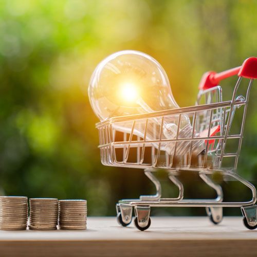Energy saving light bulb with stacks of coins and shopping cart for saving, financial and shopping concept.