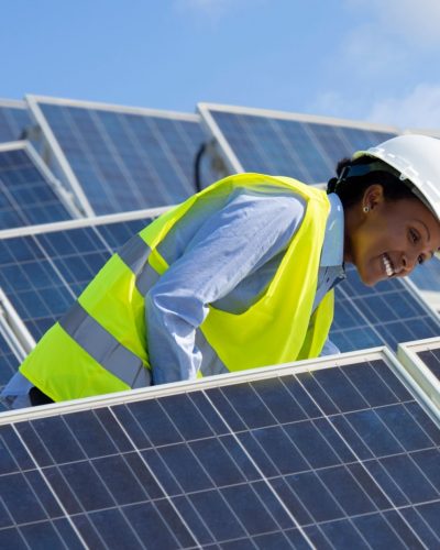 Electrical engineer woman checking solar photovoltaic panels on the roof of a solar farm.